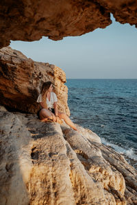 Woman sitting on rock at beach