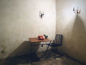 Empty chair and table against wall at home