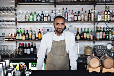 Portrait of smiling male owner standing at checkout counter in restaurant