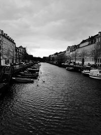 Canal amidst buildings in city against sky