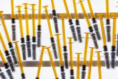 High angle view of yellow syringes in white background