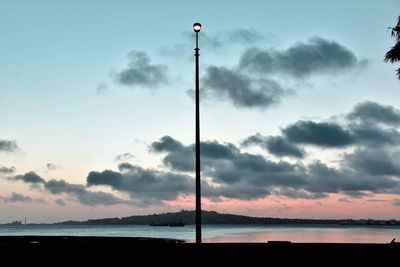 Street light on silhouette beach against sky during sunset