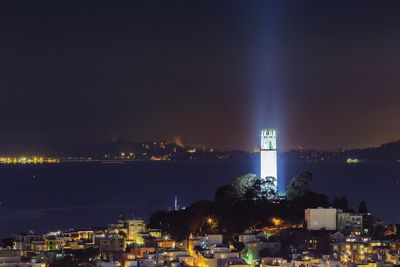 View of illuminated cityscape and coit tower against sky at night