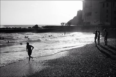 Silhouette people enjoying on sea shore