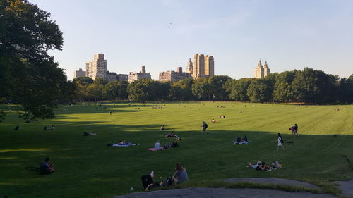 People on grass area in park against sky