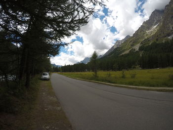 Road by trees on mountain against sky