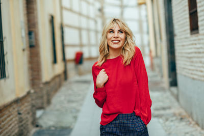 Smiling young woman standing in alley