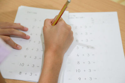 Close-up of girl writing on book at home