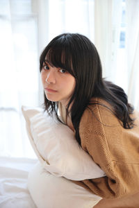 Portrait of young woman sitting on bed at home
