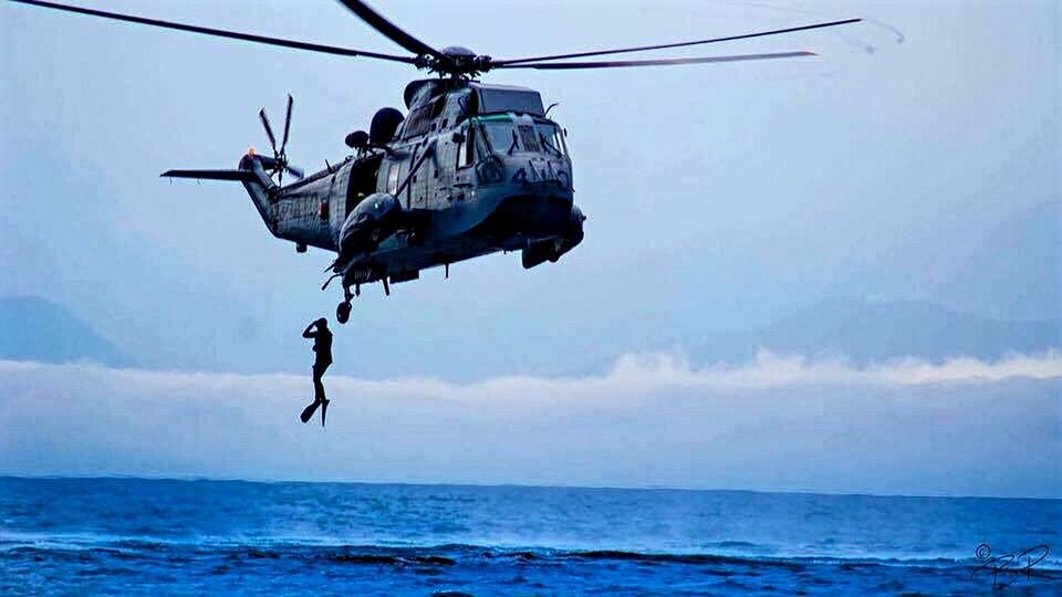 LOW ANGLE VIEW OF HELICOPTER AGAINST SEA