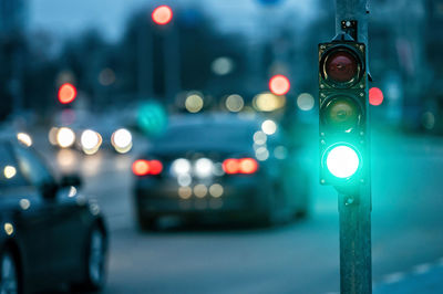 A city crossing with a semaphore on blurred background with cars in the evening streets, green light
