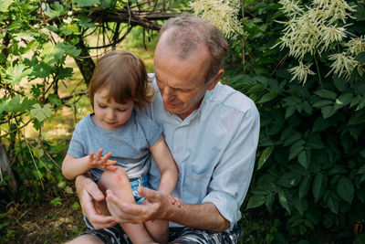 A little girl hugs her grandfather on a walk in the summer outdoors.