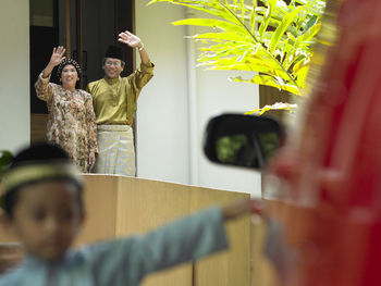 Grandparents waving while standing outside house