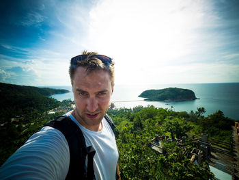 Portrait of hiker standing on mountain against sea