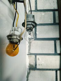 Low angle view of light bulb hanging on wall