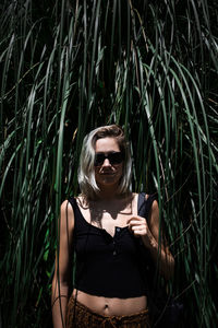 Woman wearing sunglasses standing by plants