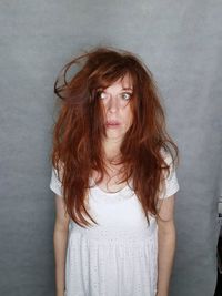Portrait of young woman standing against wall