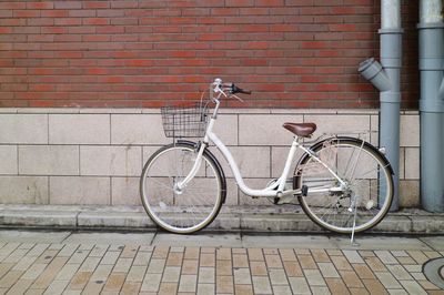 Bicycle parked against brick wall.