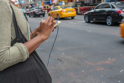 Midsection of man holding umbrella on city street