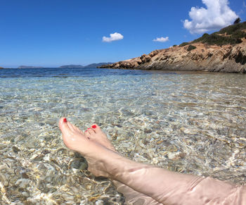 Low section of person in sea against sky