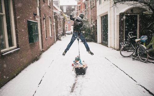 Man cycling on snow covered city in winter