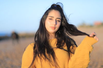 Portrait of beautiful young woman standing against sky