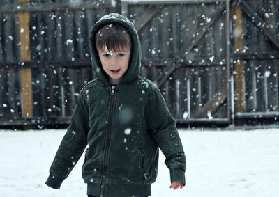 Close-up portrait of cute boy in warm clothing standing on snow