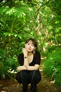 Young woman looking away while sitting on land