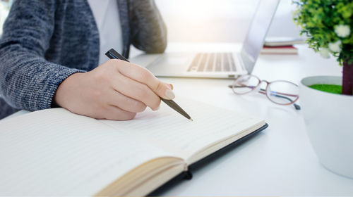 Midsection of man reading book on table