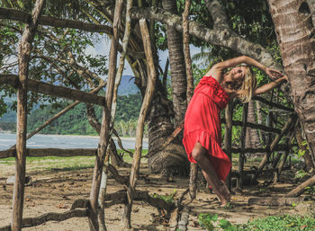 Woman standing by tree trunk in forest