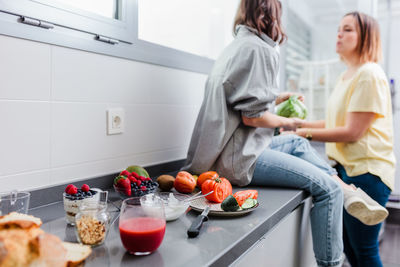 Women talking while standing in kitchen at home