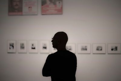 Rear view of silhouette man standing against wall at museum