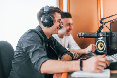 Two guys is indoors in the radio studio is busy by broadcast.