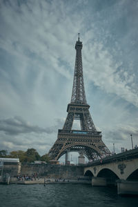 Arch bridge over river against cloudy sky