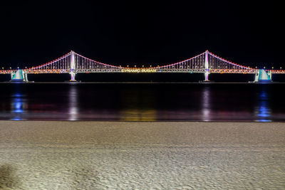 Illuminated suspension bridge over river at night