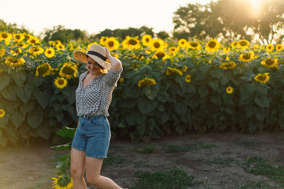 Beautiful young woman with sunflowers enjoying nature and laughing on summer sunflower field.