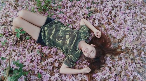 Portrait of young woman lying on pink flowers