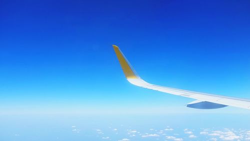 Cropped image of airplane flying against clear blue sky