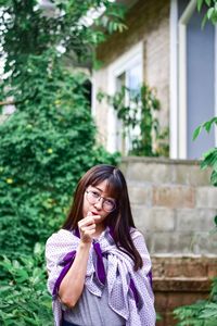 Portrait of young woman standing against plants