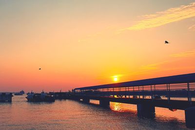 View of bridge over sea against orange sky