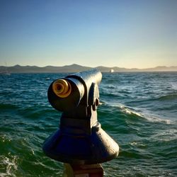Coin-operated binoculars on sea against clear sky