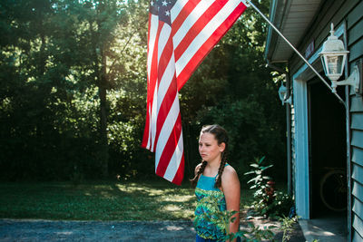 Woman with umbrella flag against built structure