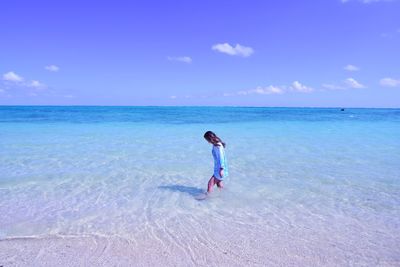 Full length of woman on beach against blue sky