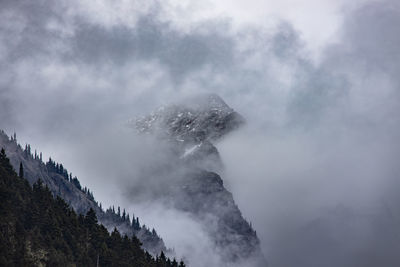 Snow capped mountain sticks out of the morning clouds	