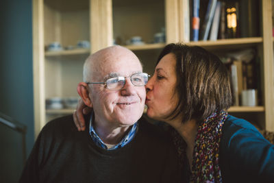 Senior woman kissing her husband at home