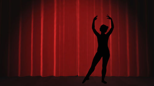 Silhouette woman standing against red curtain