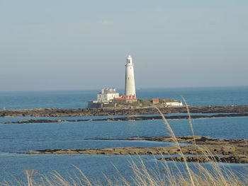 Lighthouse by sea against sky