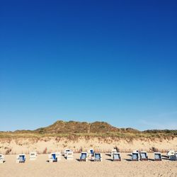 Panoramic view of sun loungers on beach against clear blue sky