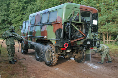 Men cleaning truck on field