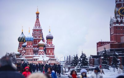 People walking on street against snow covered church in city